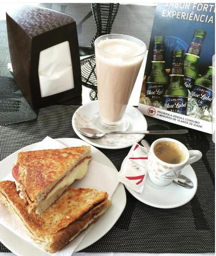a table with a sandwich and a cup of coffee at Orquidea GuestHouse Spa & Restaurant in Maputo