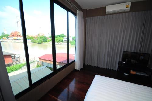 a bedroom with large windows with a view of a river at Baan Keang Chon Ayutthaya บ้านเคียงชล อยุธยา in Phra Nakhon Si Ayutthaya