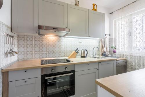 a kitchen with white cabinets and a stove top oven at Divna Apartments and Rooms in Račišće