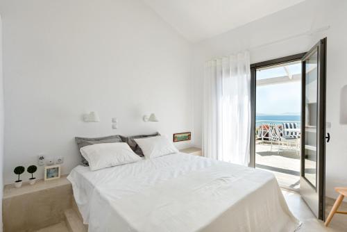 ein weißes Schlafzimmer mit einem großen Bett und einem Balkon in der Unterkunft Beach Bird Swallow in Megáli Panayía