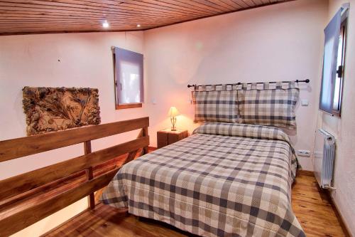een slaapkamer met een bed met een geruite deken bij La Illeta in Deltebre