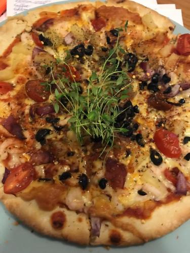 a pizza with cheese and vegetables on a plate at Sogn Hotel in Vadheim