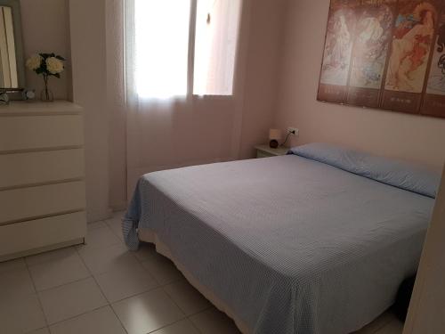 1 dormitorio con cama blanca y ventana en El Cantil, en Isla Cristina