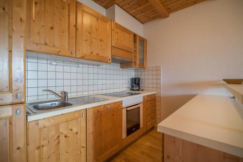 a kitchen with wooden cabinets and a sink at Apartmajsko naselje Ribniško Pohorje in Ribnica na Pohorju