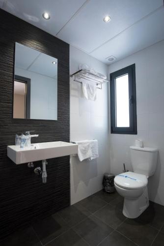 a bathroom with a sink and a toilet and a mirror at Hostal Emeritae in Merida