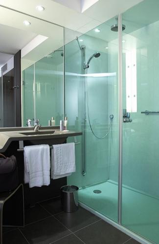 une salle de bain avec une douche en verre et un lavabo dans l'établissement Hôtel Oceania Nantes Aéroport, à Bouguenais