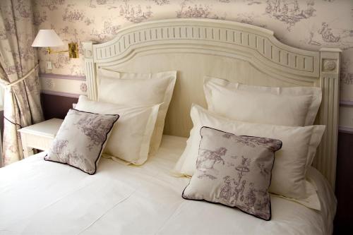 a neatly made bed with white pillows and pillows at Mercure Moulins Centre Hôtel de Paris in Moulins