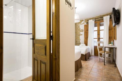 a bathroom with a shower and a bedroom at Posada de Uncastillo in Uncastillo