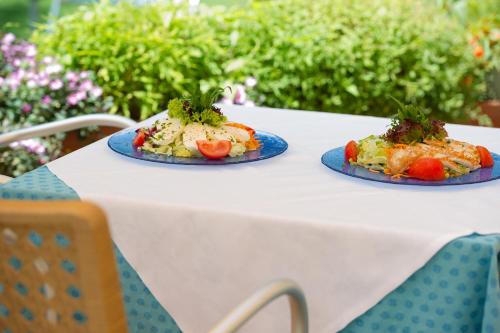 two plates of food sitting on a white table at PENSION KLUGHAMMER in Caldaro