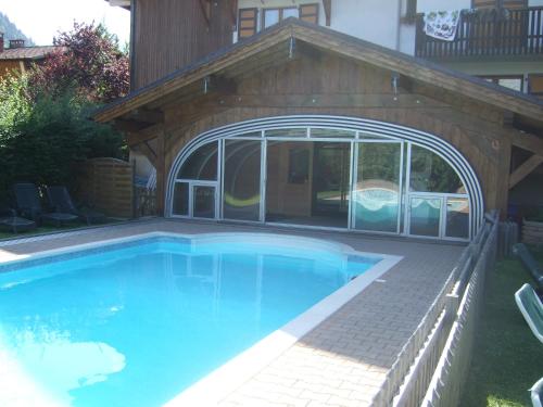 a swimming pool with a pavilion and a house at Alpen Roc in Morzine