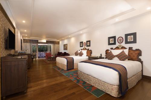 a hotel room with two beds and a television at MAYFAIR Himalayan Spa Resort in Kalimpong