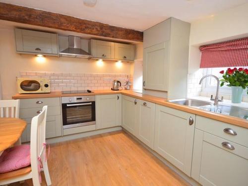 a kitchen with white cabinets and a sink and a table at Red Rose Cottage in Cheddar