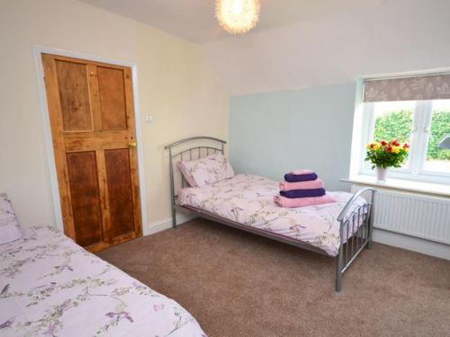 a bedroom with two beds and a window at Red Rose Cottage in Cheddar