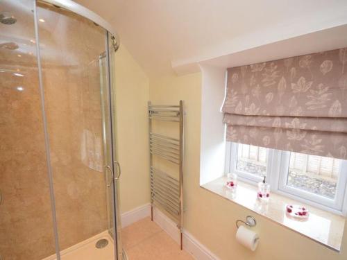 La salle de bains est pourvue d'une douche et d'une fenêtre avec un rideau de douche. dans l'établissement Red Rose Cottage, à Cheddar