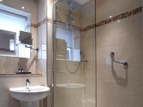 a bathroom with a glass shower and a sink at Macdonald Elmers Court Hotel in Lymington