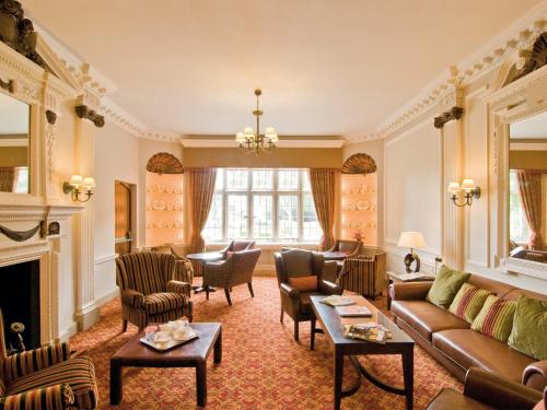 a living room with a couch and chairs and a fireplace at Macdonald Elmers Court Hotel in Lymington