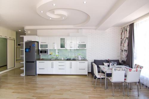 une cuisine avec des armoires blanches et une table avec des chaises dans l'établissement Batumi Real Lux, à Batoumi