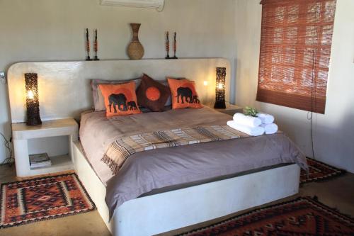 ein Schlafzimmer mit einem großen Bett mit orangefarbenen Kissen in der Unterkunft Tantebane Game Ranch in Tantebane