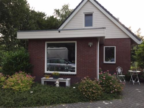 een klein rood bakstenen huis met een tafel en een raam bij B & B genieten bij Groen in Drachten