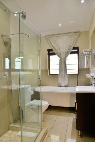 a bathroom with a shower and a toilet and a sink at Bellgrove Guest House Sandton in Johannesburg