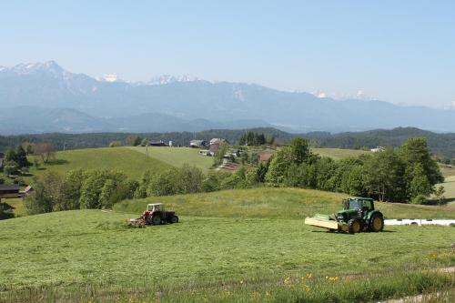 two tractors in a field with mountains in the background at Pleschinhof in Velden am Wörthersee