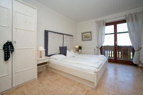 a white bedroom with a bed and a window at Pleschinhof in Velden am Wörthersee