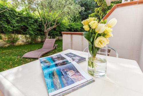 a table with a vase of flowers and a magazine at Hotel Santa Maria in Santa Maria Navarrese