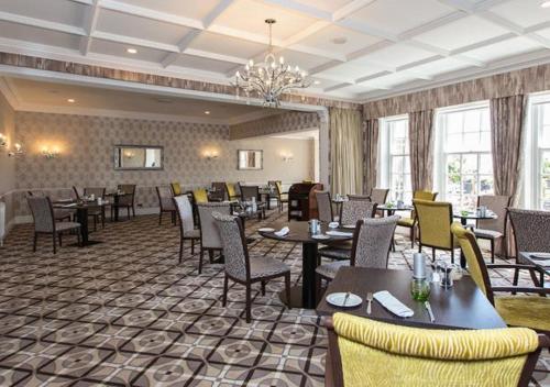 a restaurant with tables and chairs and a chandelier at Hotel Miramar in Bournemouth