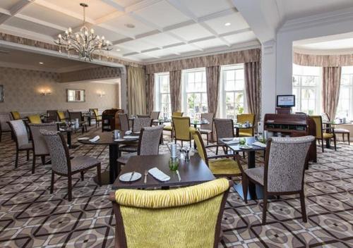 a restaurant with tables and chairs and a chandelier at Hotel Miramar in Bournemouth