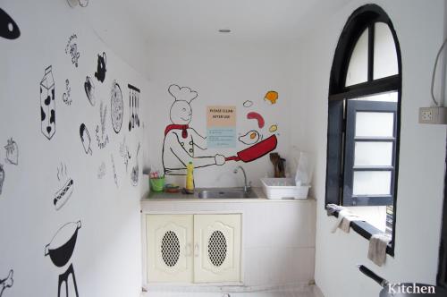 a kitchen with a sink with a chef painted on the wall at 1sabai in Bangkok