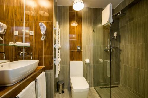 a bathroom with a shower, sink, and toilet at Science Hotel in Szeged