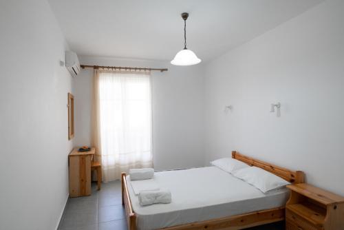 a white bedroom with a bed and a window at Afroditi Pansion in Agios Nikitas