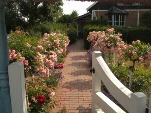 un camino de ladrillo con flores rosas y una valla blanca en Graf Luckner Hues, en Scharbeutz