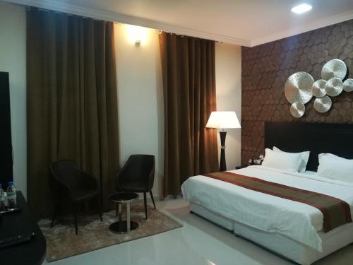 a hotel room with a bed and two chairs at Tanuf Residency Hotel in Nizwa