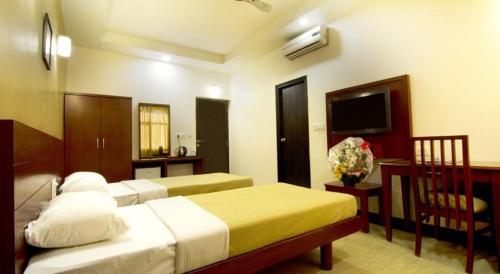 a hotel room with two beds and a television at Magic Inn in Bangalore