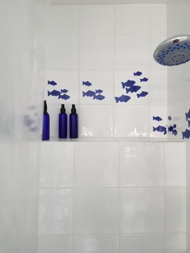un bagno con bottiglie blu su una parete bianca piastrellata di Apartment Tanja a Supetar (San Pietro di Brazza)