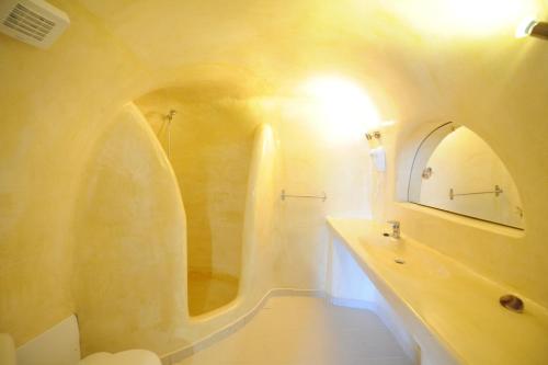 a bathroom with a tub and a sink and a mirror at Manias Fira Residences in Fira