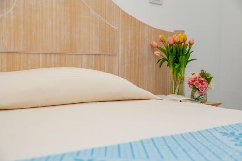 a bed with a vase of flowers on a table at Hotel Dei Pini in Alghero