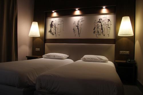 two beds in a hotel room with two lamps at Le Safari Hotel Restaurant in Carpentras