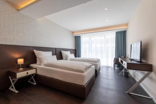 a hotel room with two beds and a television at Trip Inn Conference Hotel & Suites in Wetzlar