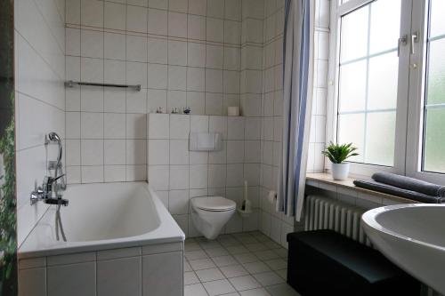 a bathroom with a tub and a toilet and a sink at Hotel-Restaurant Haus Keller in Laggenbeck
