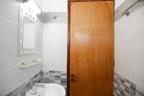 a bathroom with a wooden door and a sink at Afroditi Pansion in Agios Nikitas