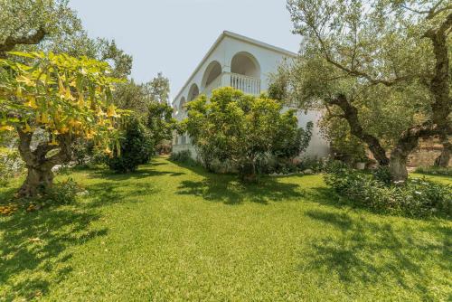 a yard with trees and a white building at Ruassi Studios in Amoudi