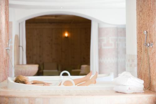a woman laying in a bath tub with a mirror at Frida am Wald in Rasùn di Sotto