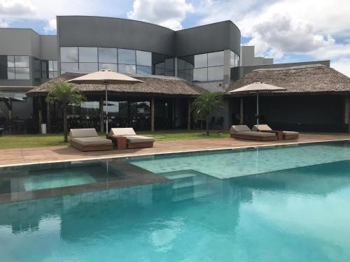 einem Pool mit Stühlen und Sonnenschirmen vor einem Gebäude in der Unterkunft Ives Hotel in Costa Rica