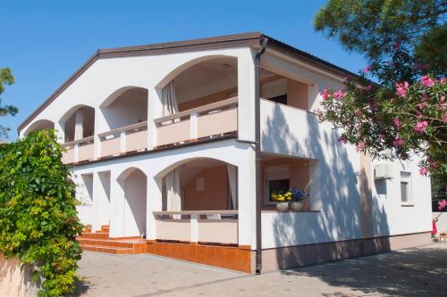 a white building with balconies and flowers on it at Apartmani Luka in Vir