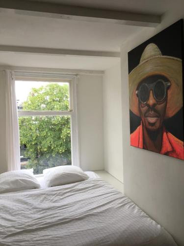 a bedroom with a painting of a man wearing sunglasses at Cozy Pijp Apartment Amsterdam in Amsterdam