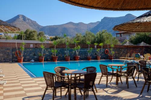 a hotel with a pool and tables and chairs at Corali Studios & Portobello Apartments in Elounda