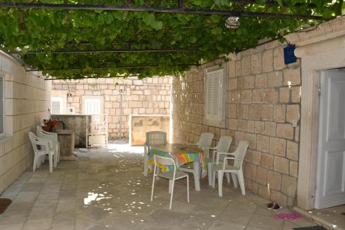 a patio with a table and chairs and a brick wall at Apartments Pavla in Orebić