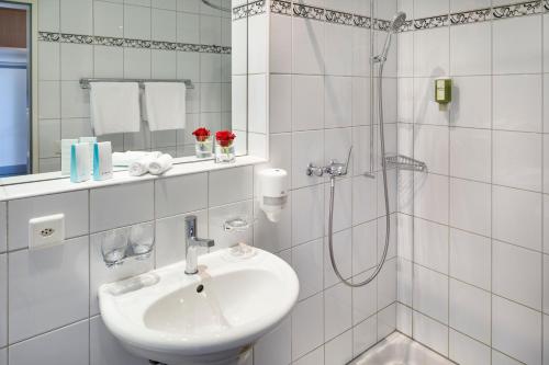 a white bathroom with a sink and a shower at Seehotel Beinwil am See Swiss Quality in Beinwil